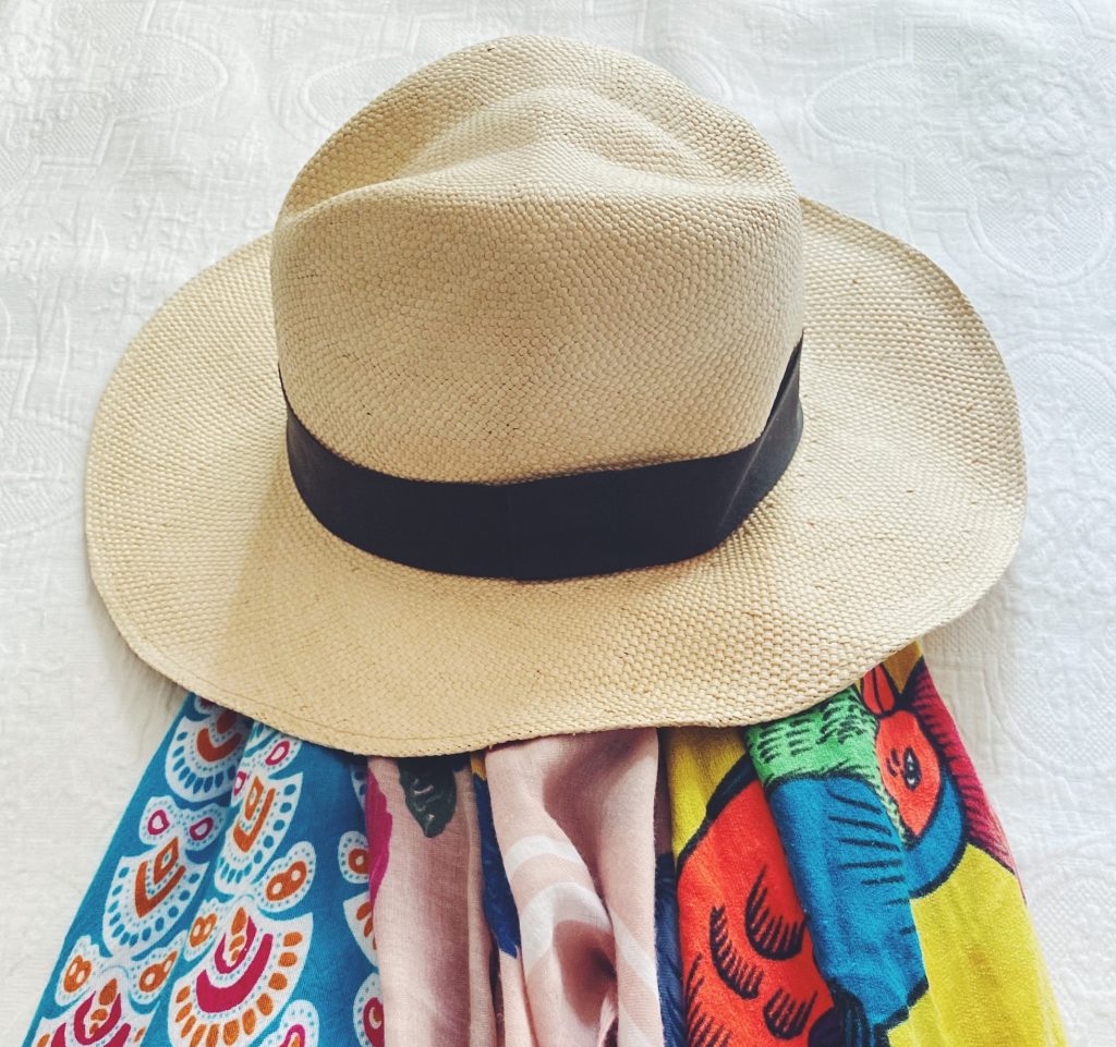 Panama hat sitting on colorful shawls and scarves.