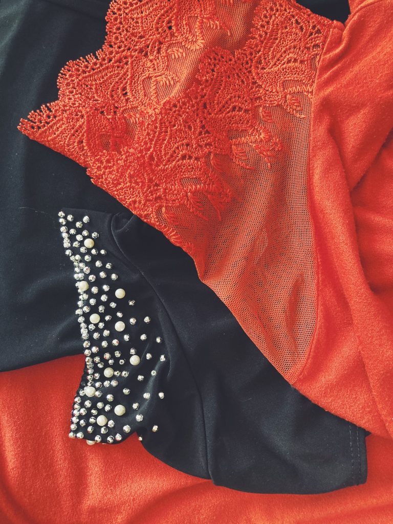 The sleeves of orange and black blouses with embroidered or sequin detail.