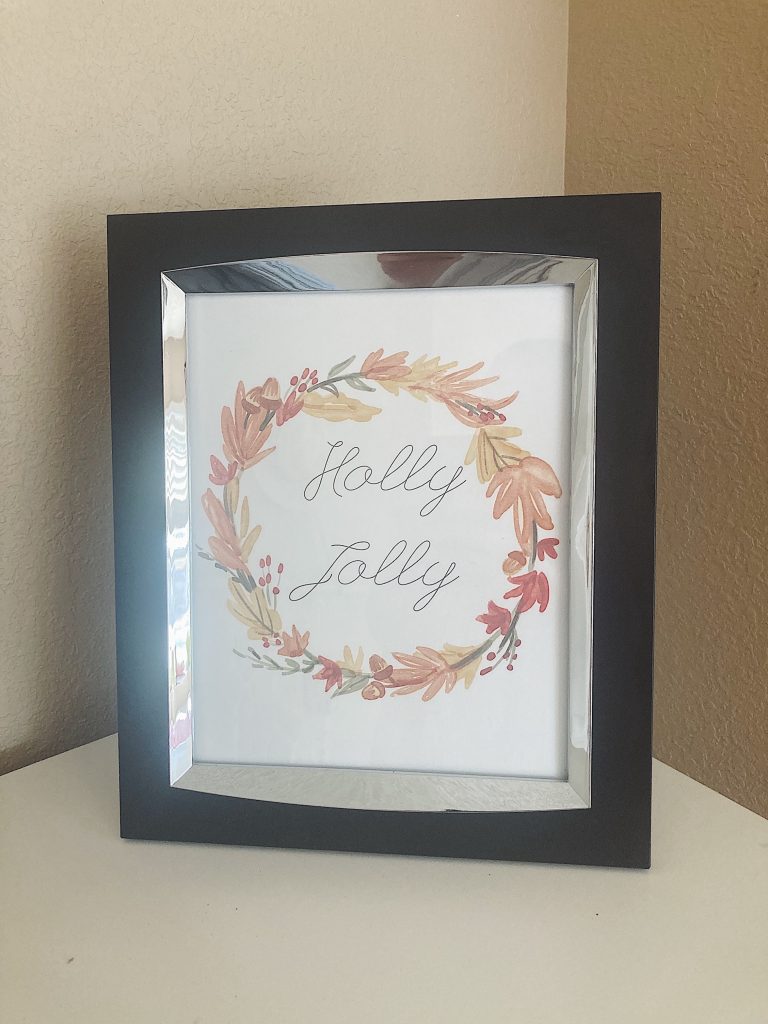 Christmas wall print that says "holly jolly" in a silver and black frame