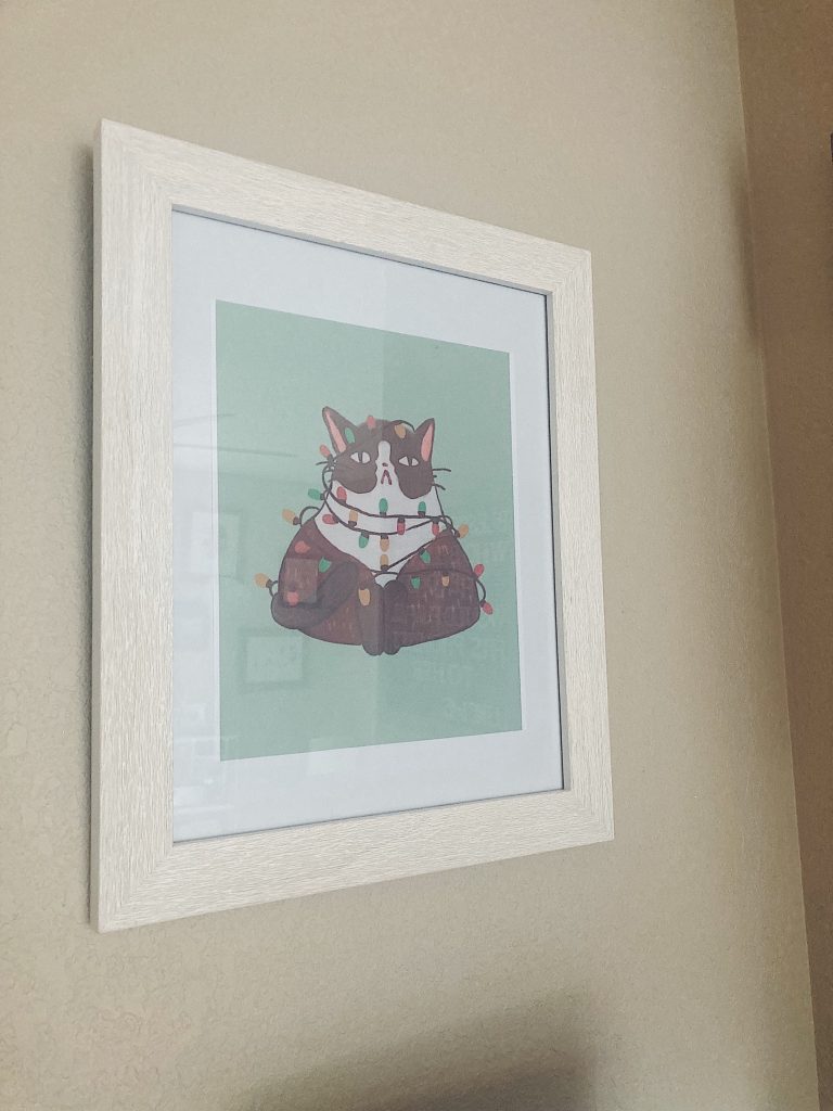 Cat wall print with christmas lights around the cat in a white frame