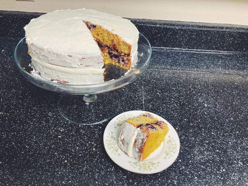 Blueberry Lemon Einkorn Cake with a slice cur out of it in an open cake stand.