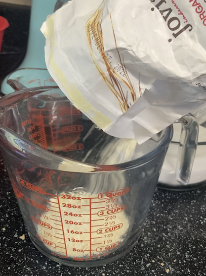 Flour being poured into a measuring cup