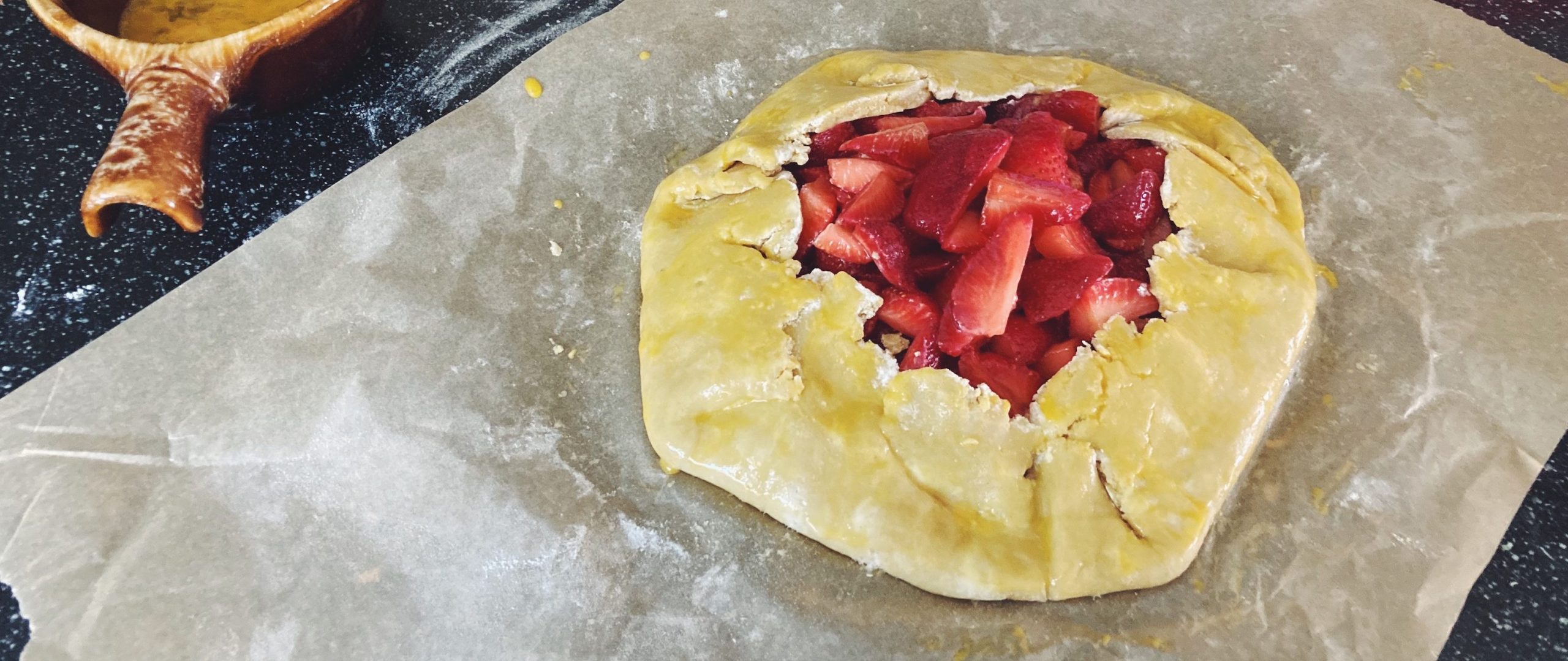 Unbaked galette with egg wash and flour next to it